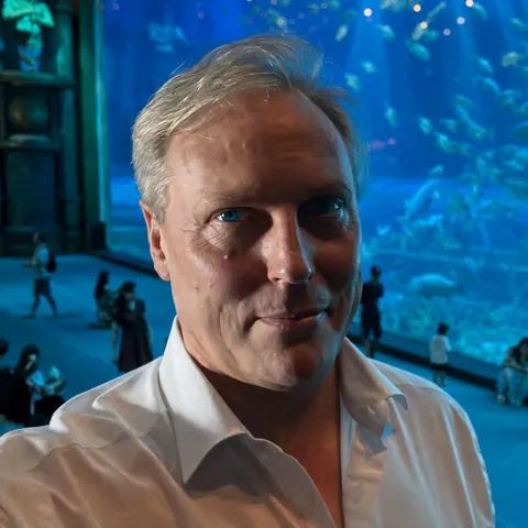 Bernard Duchenne devant la baie vitrée d'un aquarium géant